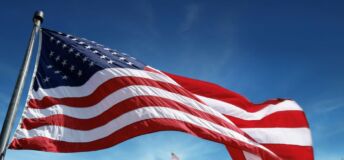 Photo of American flag flying in front of White House.